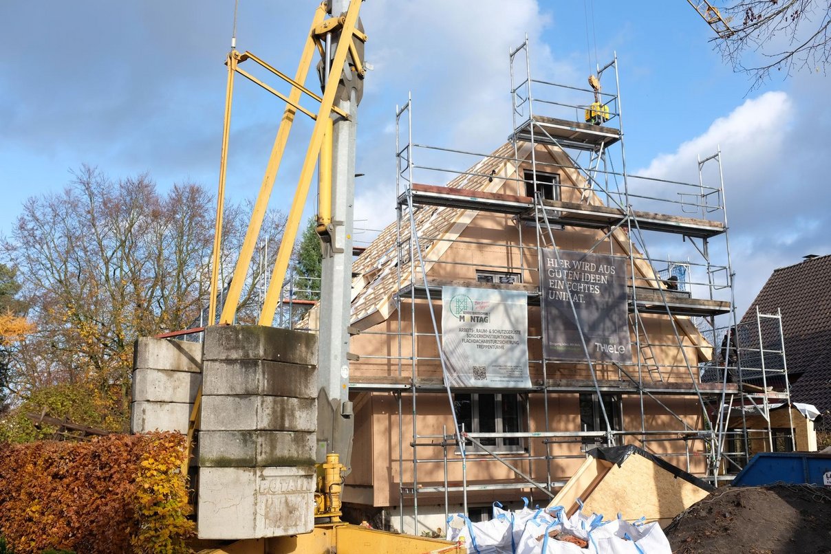 Haus in Gerüst mit Kran vom Bürgersteig aus