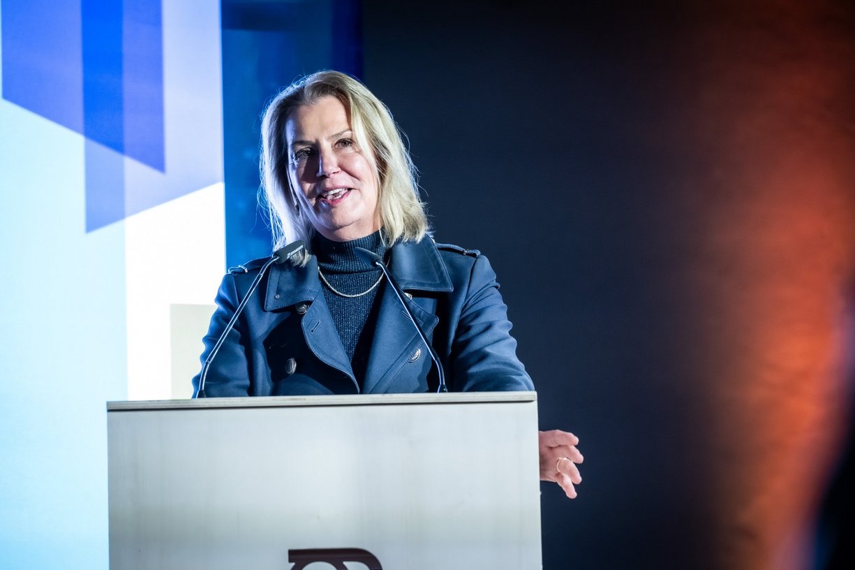 Person steht hinter Rednerpult und spricht.