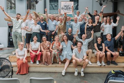 Bild zeigt eine Gruppe von Menschen, die für ein Foto posieren und die Hände in die Luft recken.