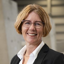 Porträt, Person mit kinnlangen Haaren und Brille, weißer Bluse und Blazer