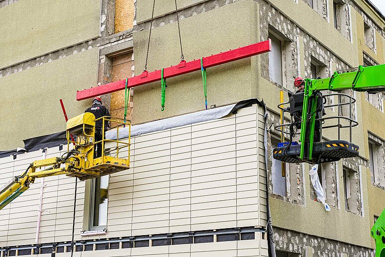 Haus teilweise mit neuer Fassade und zwei Kränen davor