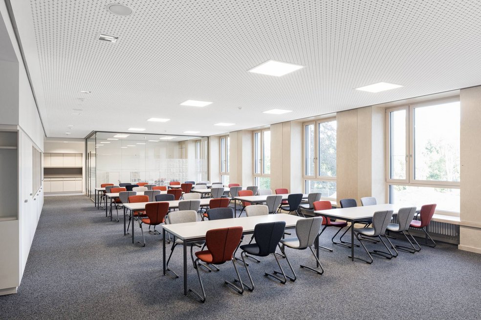Leerer Klassenraum mit roten Stühlen.