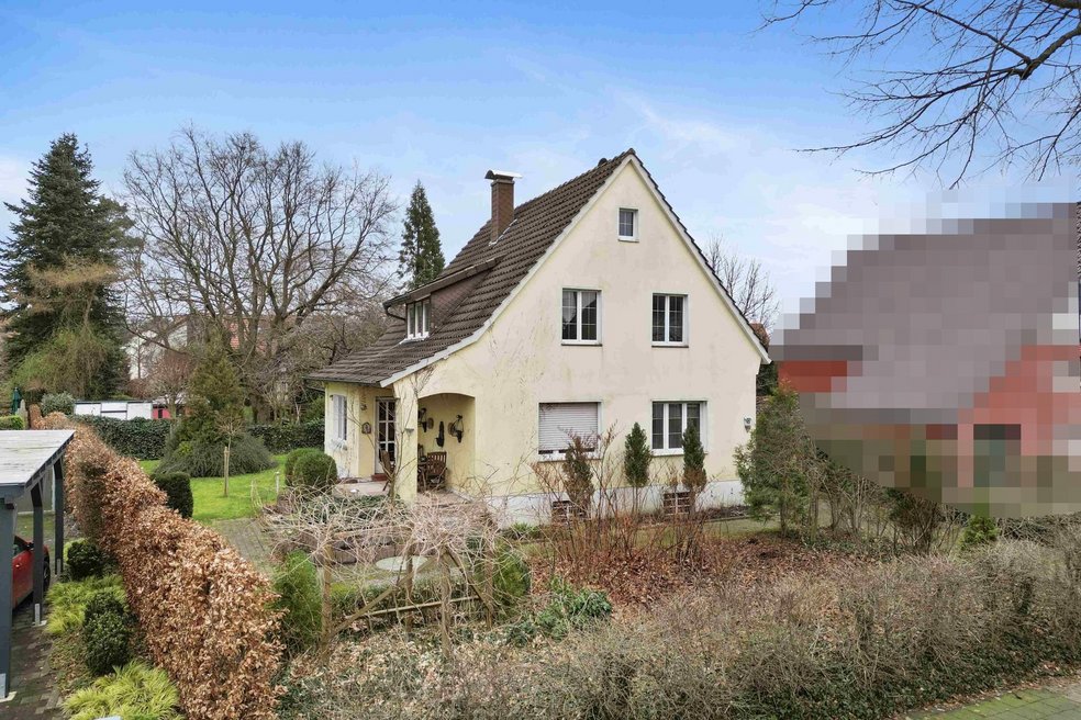 Frontansicht Einfamilienhaus mit Vorgarten und Hecke