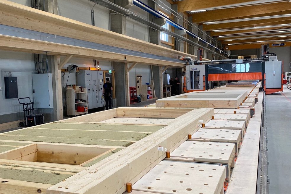 Halle in der vorgefertigte Fassadenelemente aus Holz liegen.