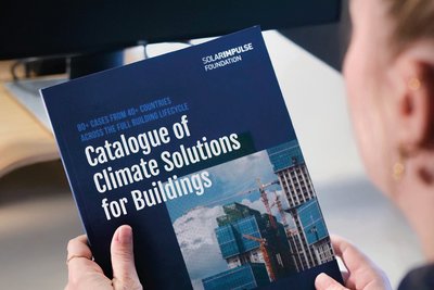 Person hält Katalog in beiden Händen, Titel: Catalogue of Climate Solutions for Buildings