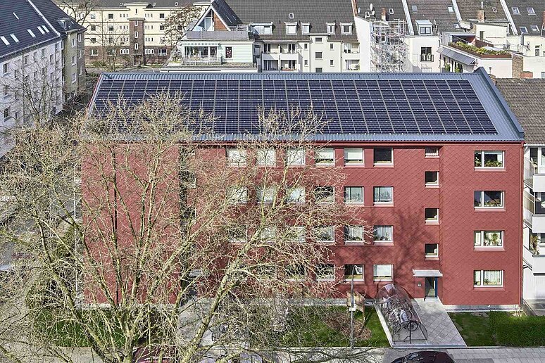 Luftansicht von Haus mit Photovoltaik hinter Baum