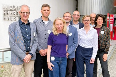 Acht Personen stehen nebeneinander für ein Gruppenbild.