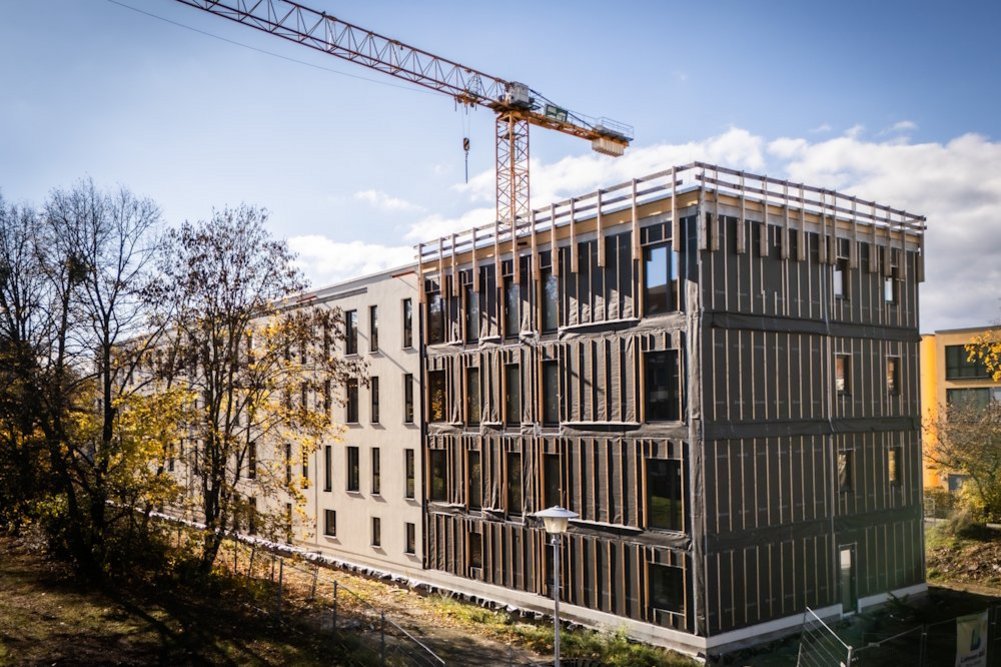 Gebäude während der Sanierung, blauer Himmel, Laubbäume und ein Kran.