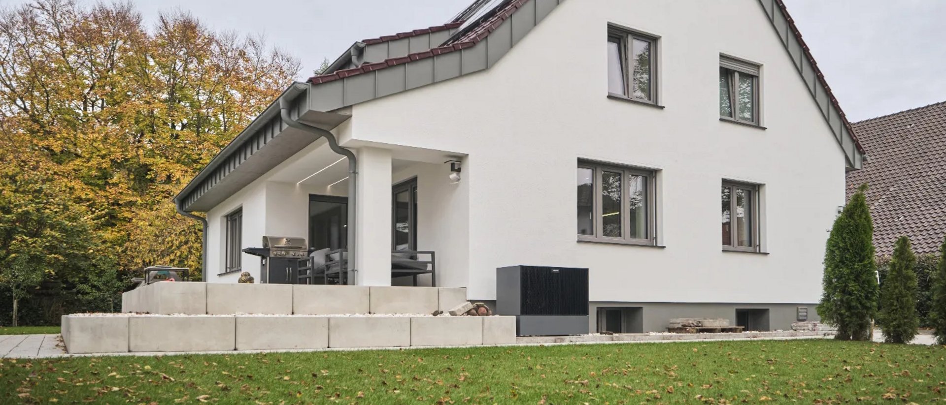 Einfamilienhaus nach der Sanierung, helle Putzfassade, Schrägdach , davor Rasenfläche