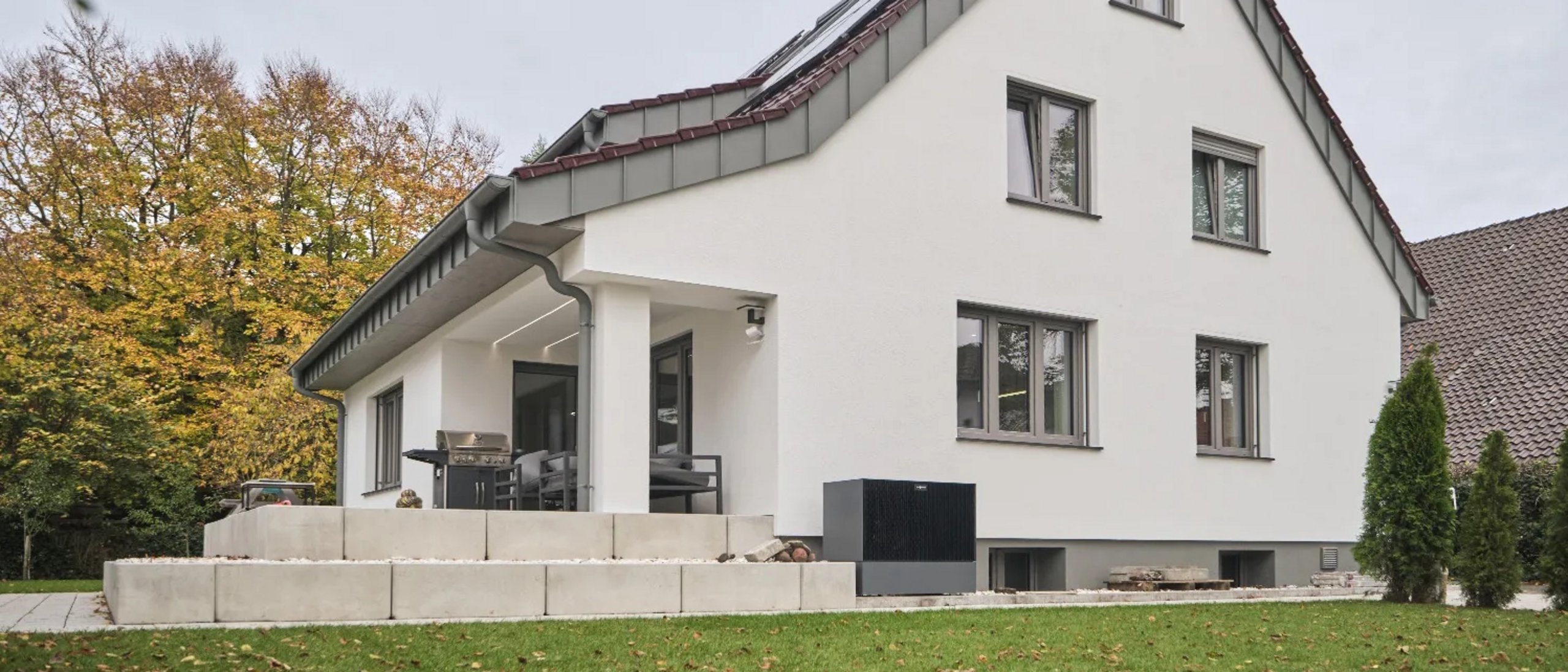 Einfamilienhaus nach der Sanierung, helle Putzfassade, Schrägdach , davor Rasenfläche