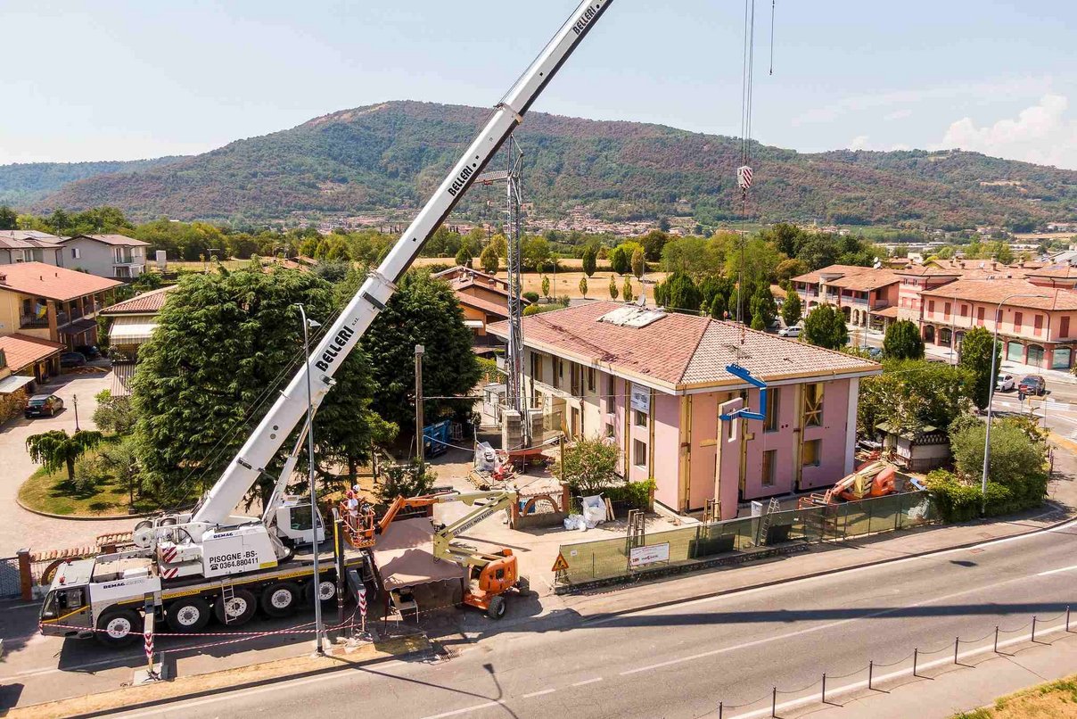 Baustelle des Energiesprong-Pilotprojektes Wohnhaus während einer Sanierung mit einem Kranfahrzeug davor, im Hintergrund grüne Hügellandschaft