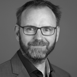 Timo Sengewald Portraitfoto in Schwarz-Weiß, Person mit Bart und Brille
