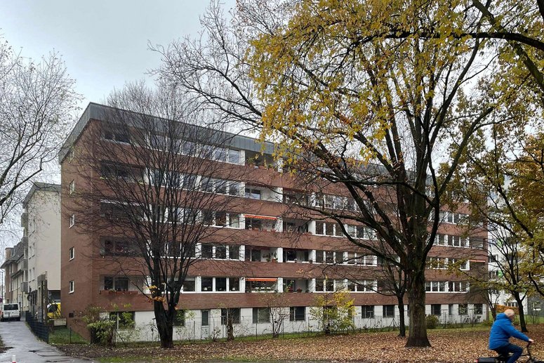 Mehrfamilienhaus fünfgeschossig mit Balkonen und Flachdach, davor Laubbäume