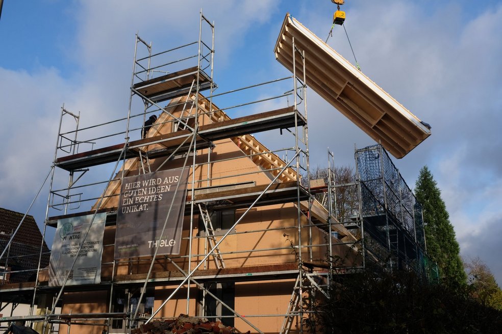 Haus in Gerüst mit Kran an dem Fassadenelement hängt