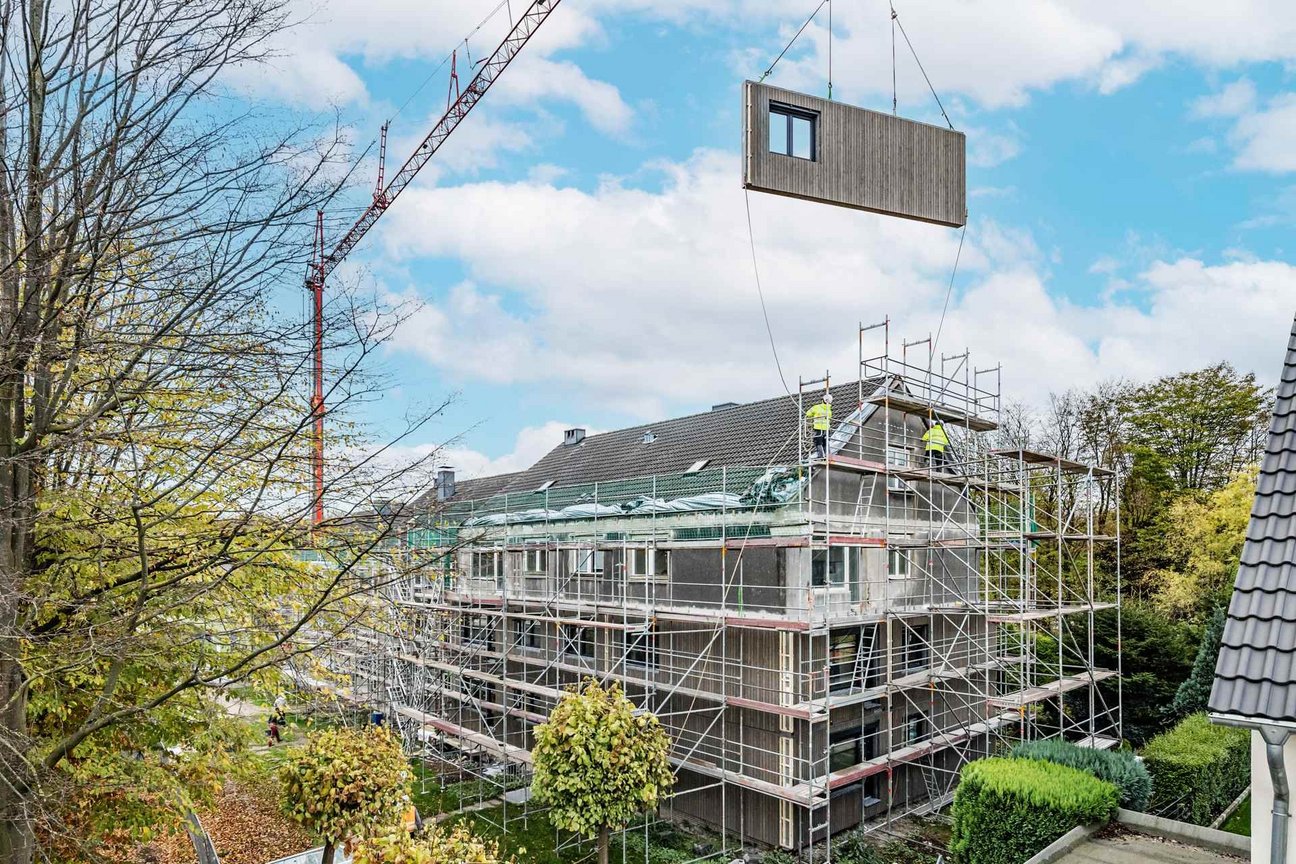 Fliegende Fassaden werden per Kran transportiert. Baustelle mit Kran und Fassadenelementen