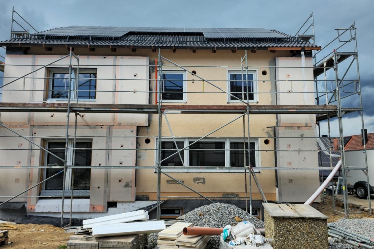 Einfamilienhaus in Baustelle mit Gerüst, Fassadenarbeiten im Gang