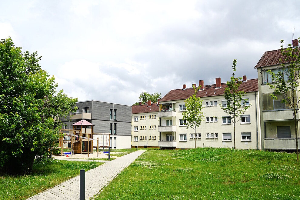 Wohngebiet mit Mehrfamilienhäusern, dreigeschossig mit Schrägdach, davor Grünflächen und Gehweg