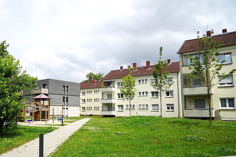 Wohngebiet mit Mehrfamilienhäusern, dreigeschossig mit Schrägdach, davor Grünflächen und Gehweg