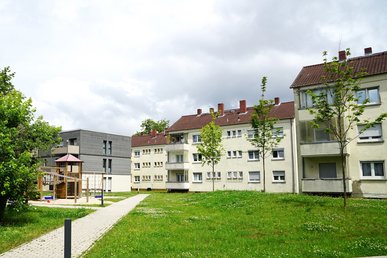 Wohngebiet mit Mehrfamilienhäusern, dreigeschossig mit Schrägdach, davor Grünflächen und Gehweg