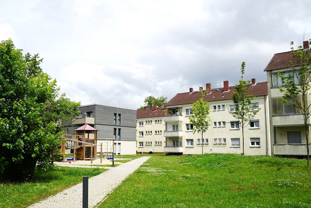 Wohngebiet mit Mehrfamilienhäusern, dreigeschossig mit Schrägdach, davor Grünflächen und Gehweg