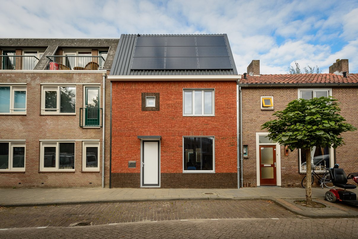 Energiesprong-Pilotprojekt, Tilburg/ Niederlande 2014 Reihenhaus nach Sanierung mit roter Backsteinfassade und Solaranlage auf dem Schrägdach, links und rechts angrenzend weitere Häuser