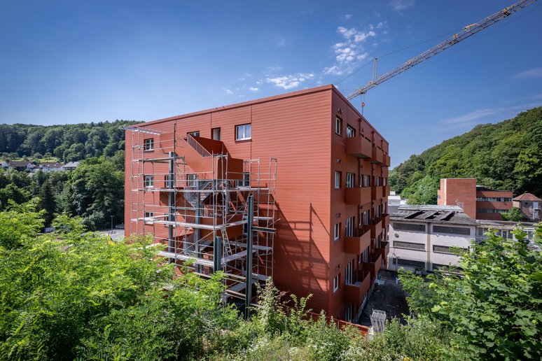 Gebäude während Sanierung umgeben von Grünflächen, Laubbäumen und weiteren kleineren Gebäuden