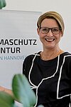 Frau vor einem Aufsteller mit der Aufschrift "Klimaschutz Agentur"