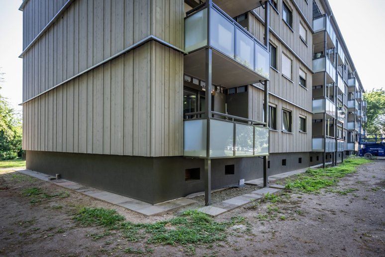 Baudetail: Blick auf die neu sanierte Fassade mit Balkon und Sockel