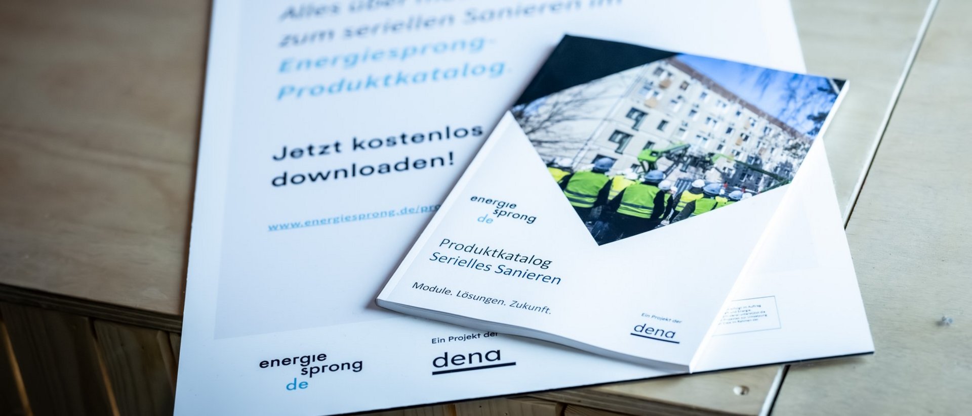 Produktkatalog Serielles Sanieren liegt auf Holzboden mit Hinweisschild: Frisch gedruckt.