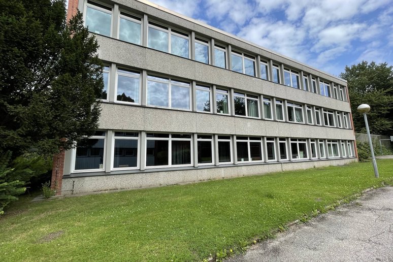 Außenansicht eines dreigeschossigen Schulgebäudes, davor Rasenfläche und Weg