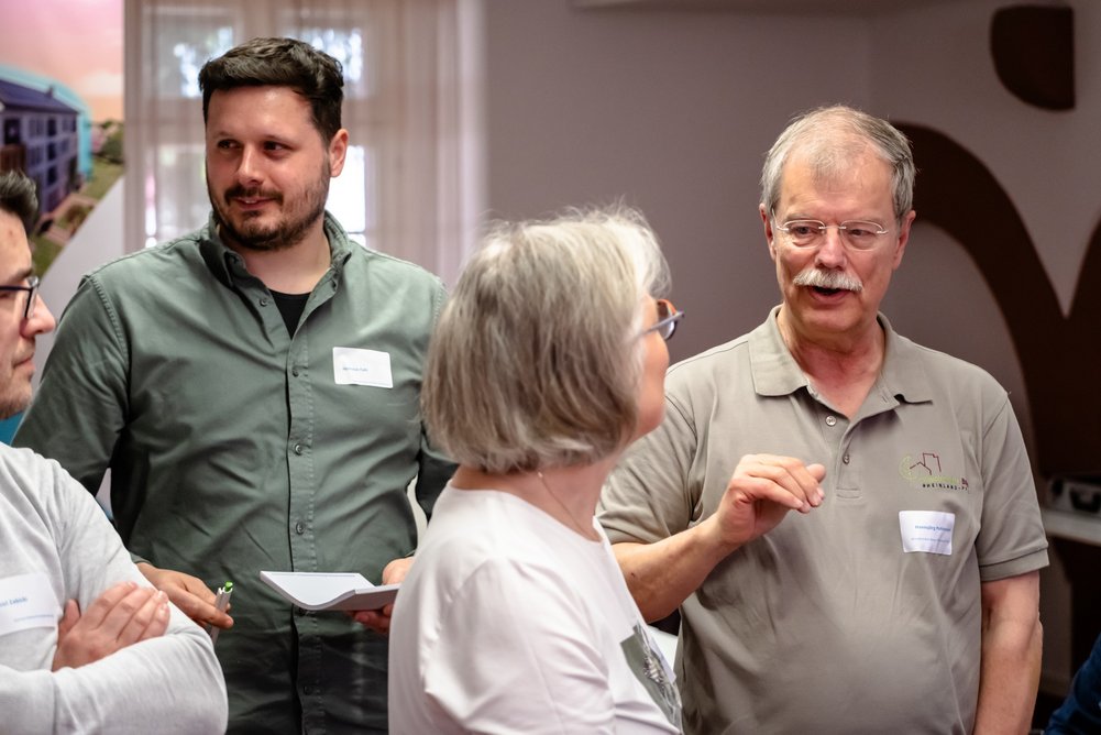 Vier Personen stehen beisamen und unterhalten sich teils.