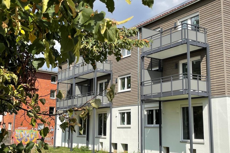 Mehrfamilienhaus dreigeschossig mit angesetzten Balkonen, davor Grünfläche