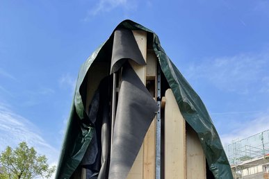 Fassadenelemente auf einer Ladefläche, abgedeckt mit dunkler Plane