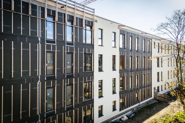 Fassade eines viergeschossigen Gebäudes während der Sanierung. Ein Teil der Fassade ist noch nicht fertiggestellt.