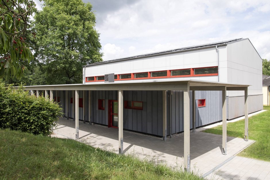 Seitlicher Blick auf Turnhalle mit überdachtem Eingangsbereich