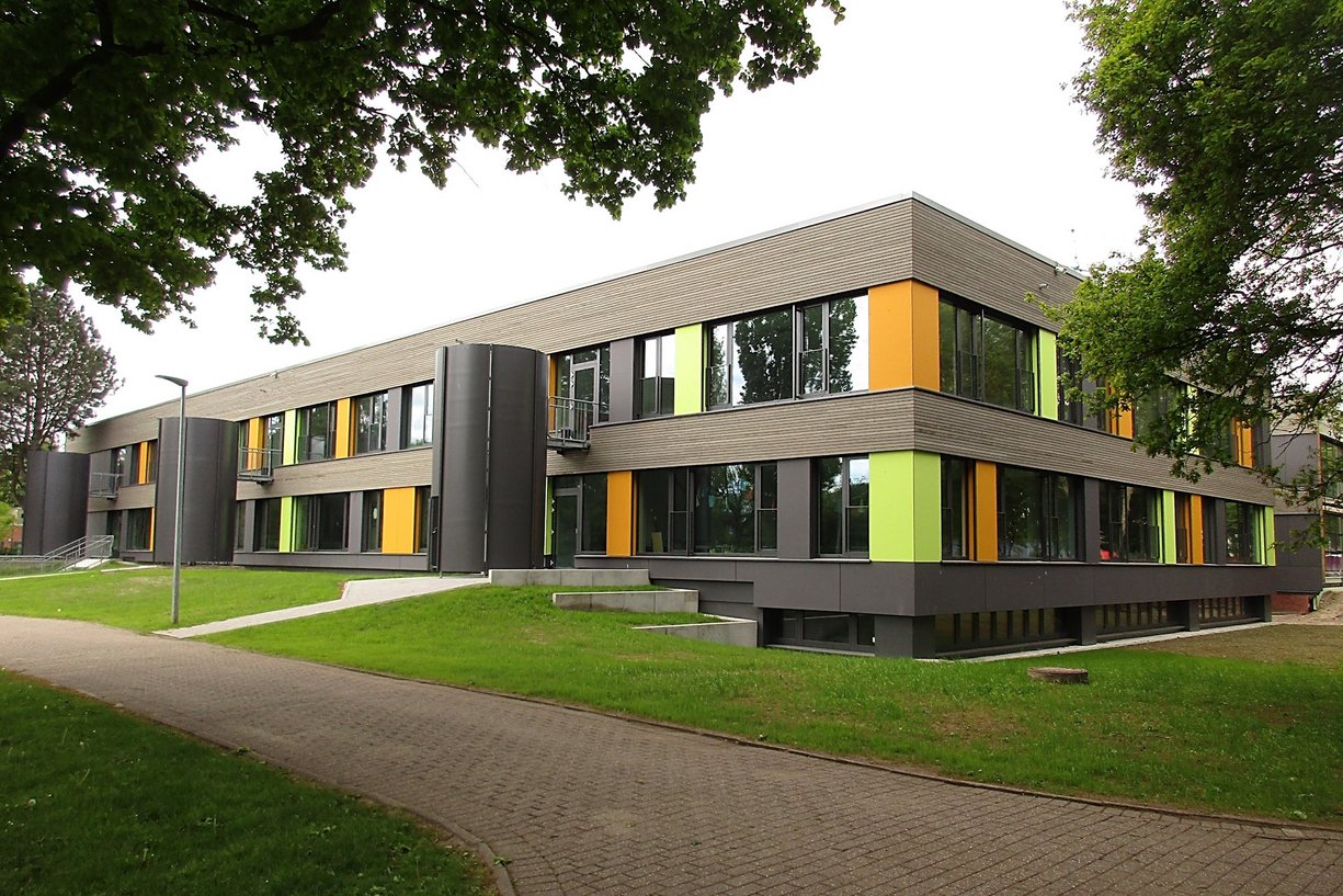 Die Integrierte Gesamtschule Kreyenbrück in Oldenburg wurde innerhalb der Sommerferien saniert. Saniertes Schulgebäude zweigeschossig, davor Grünflächen und Wege
