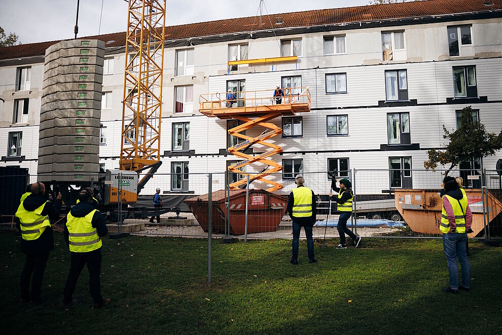 Mehrfamilienhaus während der Sanierung, davor eine Hebebühne zur Montage der Fassadenelemente