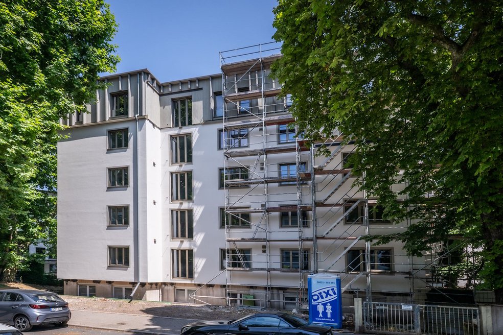 Wohngebäude viergeschossig plus Aufstockung während Sanierung, davor Straße mit parkenden PKWs