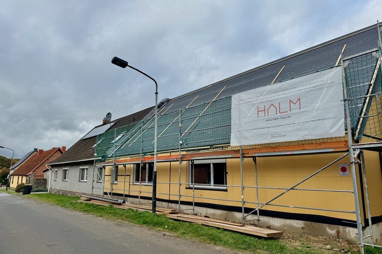 Bild zeigt Straße mit Doppelhaus davon eine Hälfte eingerüstet