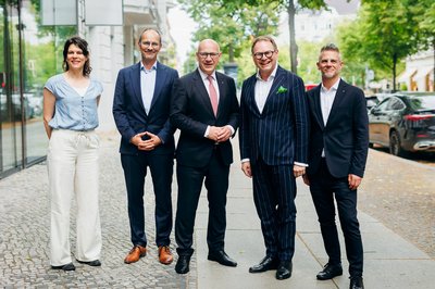 Fünf Personen stehen nebeneinander auf einem Fußweg für ein Gruppenbild.