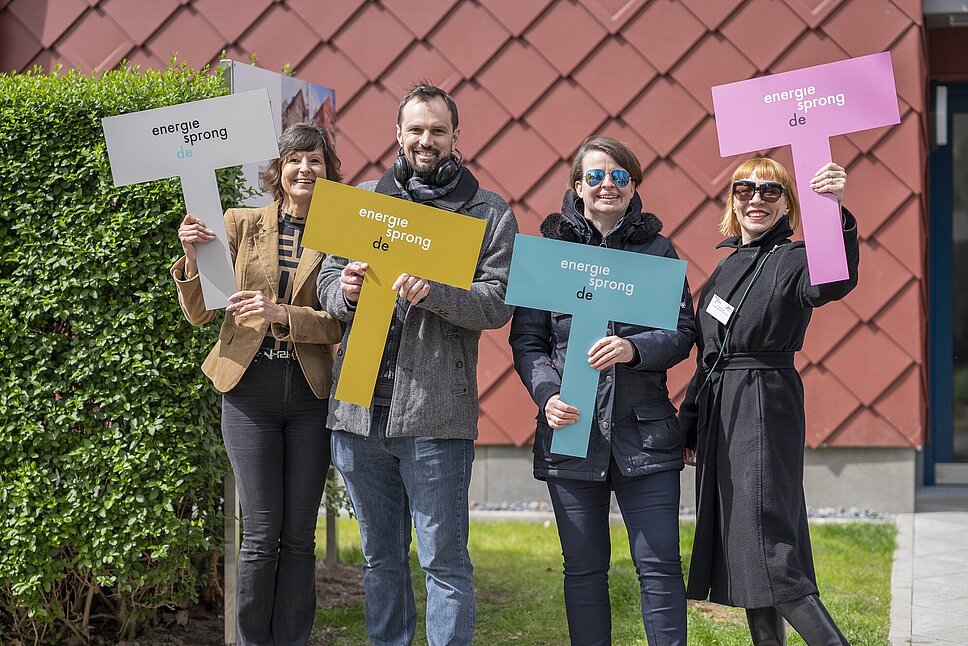 Fünf Personen stehen nebeneinander und halten je ein farbiges Schild in der Hand. Aufschrift: energiesprong.de