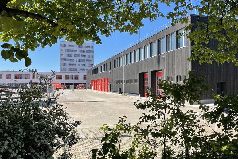 Blick durch Laubzweige auf die sanierte Feuerwache Charlottenburg