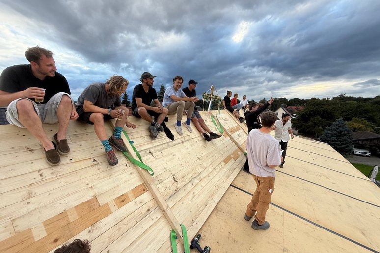 Menschen sitzen auf einem Holzdach