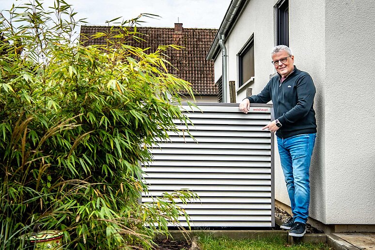 Eigentümer vor Wärmepumpe im Garten