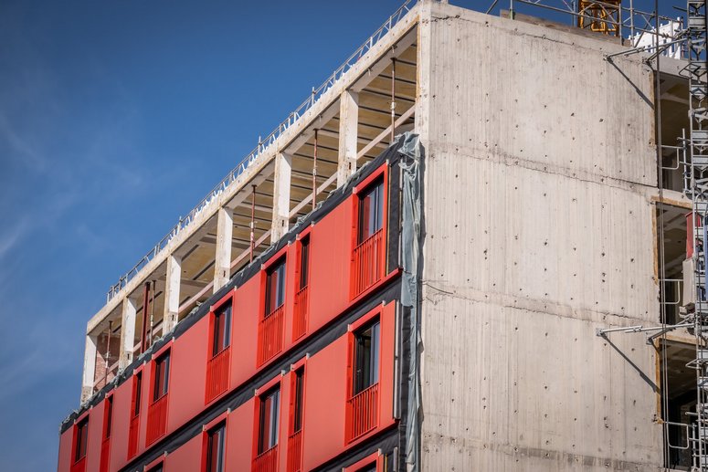 Gebäude während der Sanierung, Ein Teil der vorgefertigten Fassadenelemente sind bereits montiert. Im Hintergrund blauer Himmel.