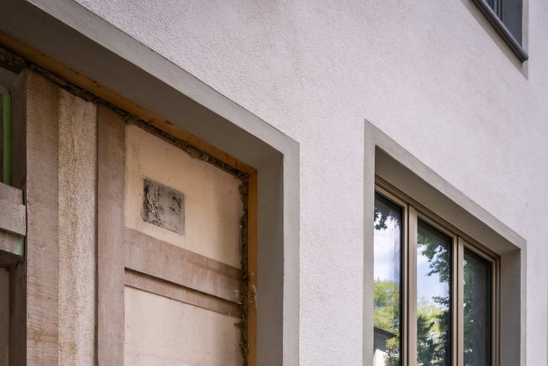 Baudetail: alter Gebäudesockel, darüber montiertes Fassadenelement mit Fenster