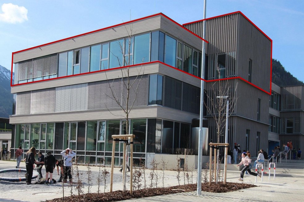 Modernes Schulgebäude nach Sanierung, davor Schulhof mit Kindern