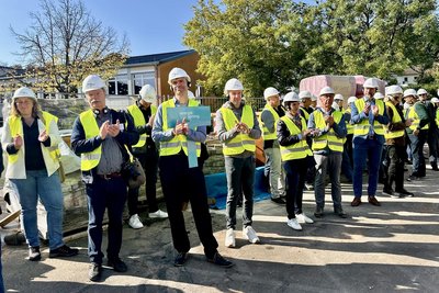 Bild zeigt Menschen auf einer Baustelle mit Warnwesten und Helmen