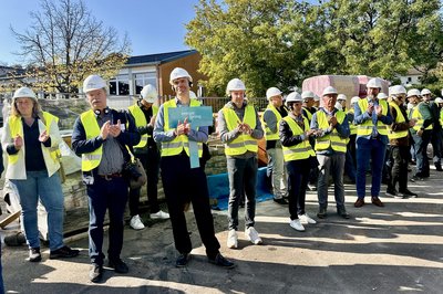 Bild zeigt Menschen auf einer Baustelle mit Warnwesten und Helmen