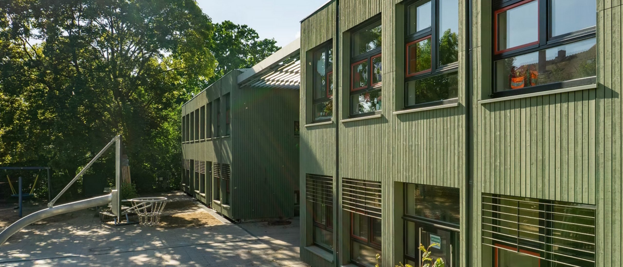 Außenansicht Kita mit grüner Holzfassade